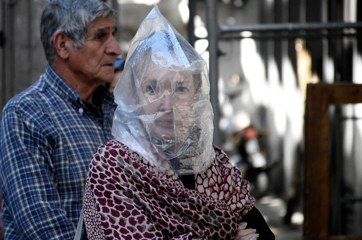 Una jubilada con protección improvisada en Rosario hace cola para cobrar su crédito.  Foto: Juan J. García
